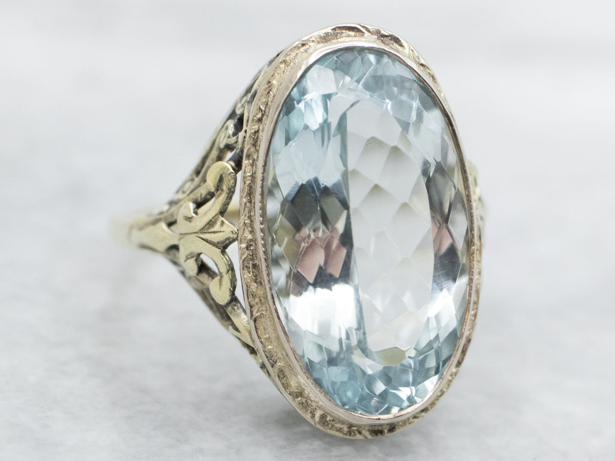 Anillo con solitario de topacio azul de talla ovalada en oro blanco y verde de dos tonos