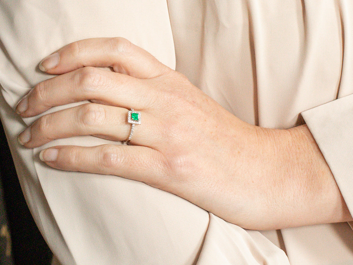 Anillo de compromiso moderno con halo de diamantes y esmeraldas cuadradas